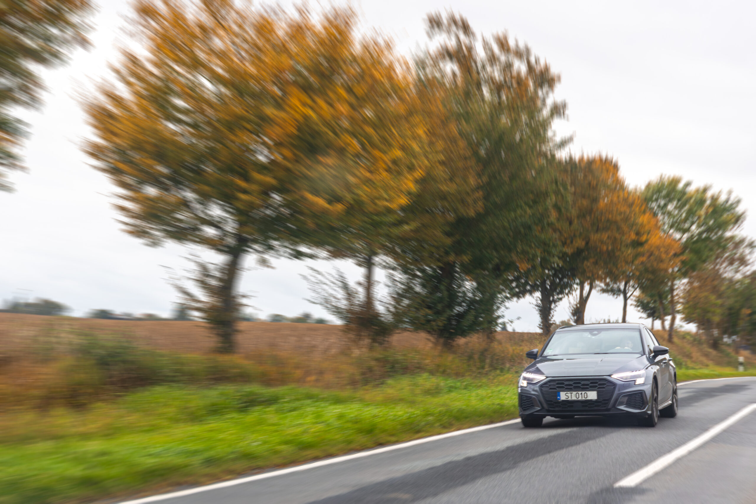 Voiture qui roule sur une voie avec des arbres sur le côté, effet photo vitesse